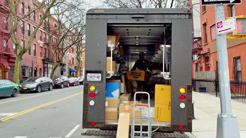 Delivery worker loading packages into open cargo truck on city street Stock Footage 335203374