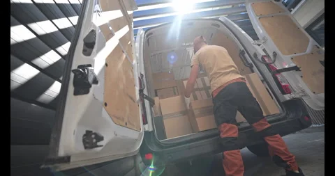 Delivery Worker Loading Packages Into a Van at a Warehouse During Daylight Hours Stock Footage 281768497