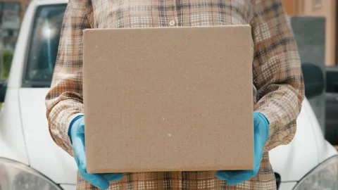 Delivery worker in protective blue gloves holding cardboard parcel box in f.. Vídeos de archivo 334586720