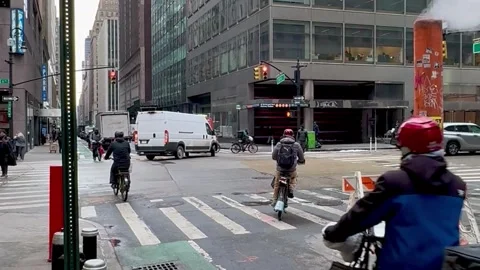 Delivery workers riding electric bikes in midtown Manhattan Stock Footage 317728992