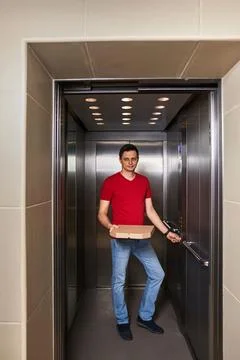 Deliveryman holding pizza box in elevator, food delivery 스톡 사진