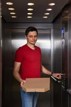 Deliveryman holding pizza box in elevator, food delivery 스톡 사진