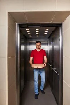 Deliveryman holding pizza box in elevator, food delivery 스톡 사진