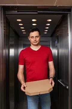 Deliveryman holding pizza box in elevator, food delivery 스톡 사진