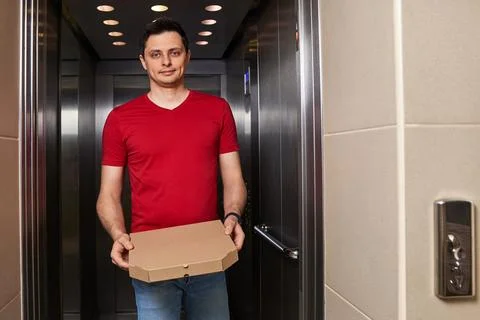 Deliveryman holding pizza box in elevator, food delivery 스톡 사진