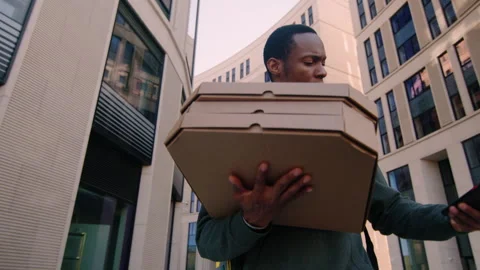 A deliveryman with pizza boxes will check the customer's address on the phone Stock Footage 254099336