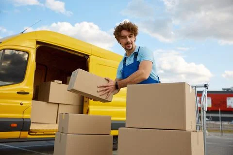 Deliveryman stacking parcel boxes into trolley cart providing courier service 스톡 사진