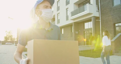 Deliveryman worker wearing cap and medical mask walking the street and carrying Stock Footage 129559535