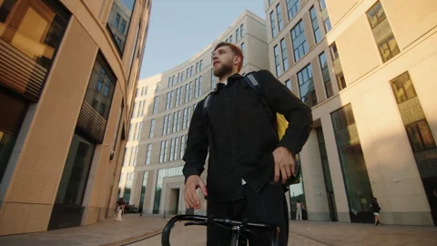 A deliveryman with a yellow backpack in search of the correct customer address Stock Footage 242993814