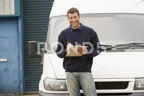 Deliveryperson standing with van writing in clipboard smiling Stock Photos