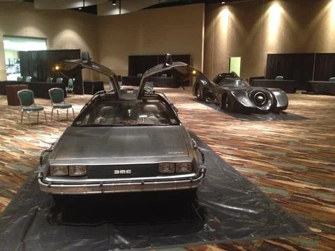 Delorean Time Machine &amp; Batmobile parked on showroom floor Stock Photos