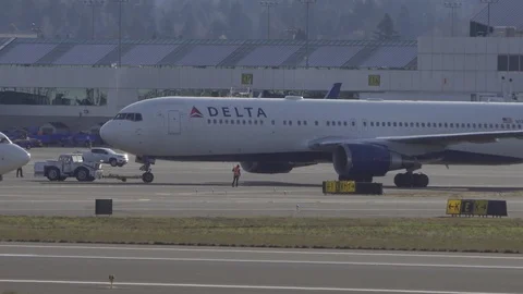 Delta Airlines 767 push back and a Boeing 737 crosses in front of it. Video stock 121688901