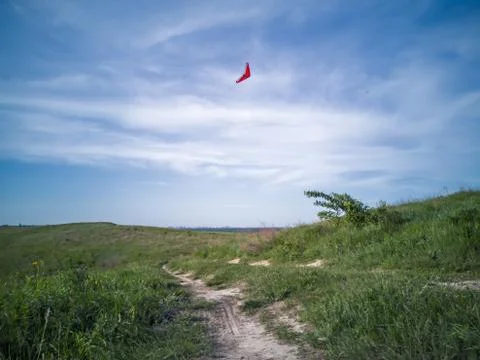 Delta plane gliding and floating in blue sky above green hill with earthy pat Stock Photos