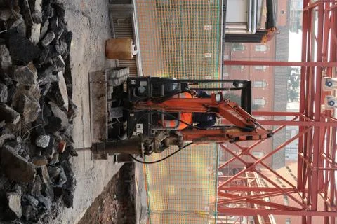 Demolition of the asphalt of a road with a jackhammer. Small excavator with d Stock Photos