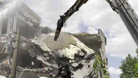 Demolition by a demolition machine. Spraying water to prevent dust formation. Stock Footage 243316404