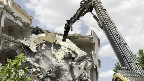 Demolition by a demolition machine. Spraying water to prevent dust formation. Stock Footage 243317529
