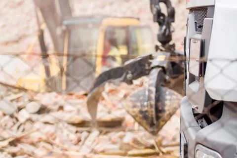Demolition industry machine taking down walls of old factory building Stock Photos