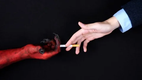 Demon hand gives a cigarette to the man. Top view