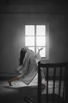 Demon inside. Terrifying woman with black hair, in white long gown standing in Stockfoto's