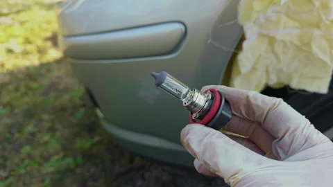 Demonstrating safe halogen bulb installation in car headlight assembly Stock Footage 332354926