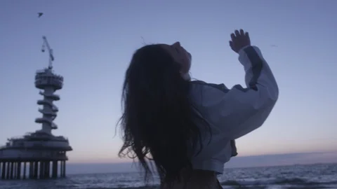 Den Haag Beach Package 3 | woman gets dizzy after spinning fun dance on beach Stock Footage 116186699
