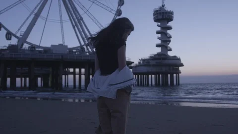 Den Haag Beach Package 7 | woman walking alone on beach next to panorama wheel Stock Footage 116189590