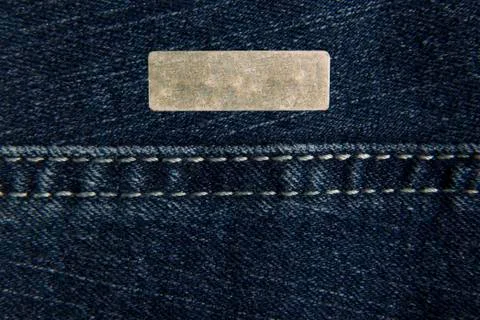 Denim blue fabric with one rectangular metal label for your text. The texture Stock Photos