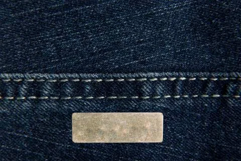 Denim blue fabric with one rectangular metal label for your text. The texture Stock Photos