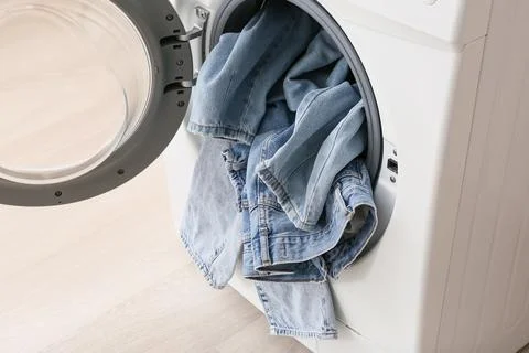 Denim jeans in front loading washing machine Fotos de archivo
