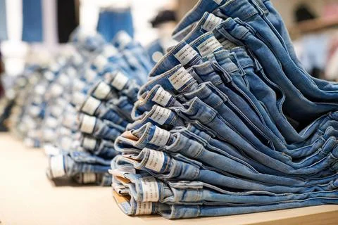 Denim jeans stack on wood table in clothing store, shopping Fotos Stock