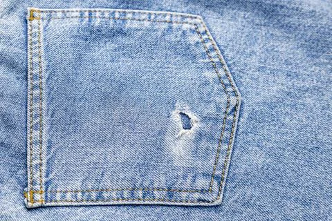 Denim texture. Back torn pocket of blue jeans close up. 库存照片