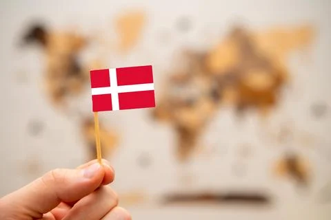 Denmark flag in mans hand on the world map background. Stock Photos