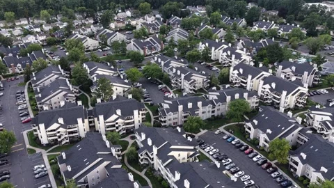 Dense apartment complex with dark angled rooftops fills wooded property in Stock Footage 342576964