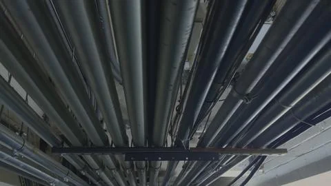 Dense Bundle of Industrial Metal Conduits and Pipes on Ceiling Foto stock