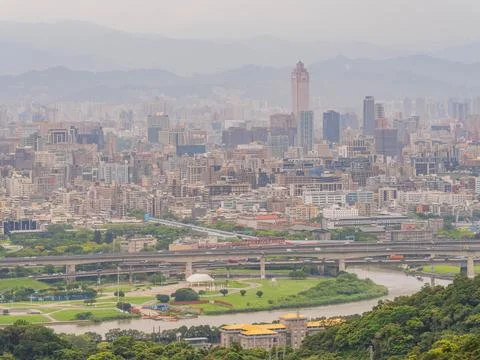 Dense city skyline rises above river and elevated highway infrastructure Stock Photos
