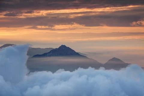 Dense cloud layer with conical peak and orange morning mist Stock Photos