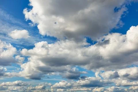 Dense clouds fill the blue sky with their gray-white caps. Stock Photos
