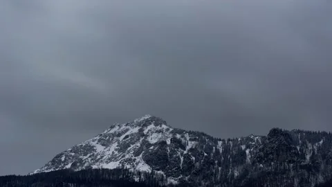 Dense clouds over a rocky snowy peak. Windy winter weather. Video stock 152492546