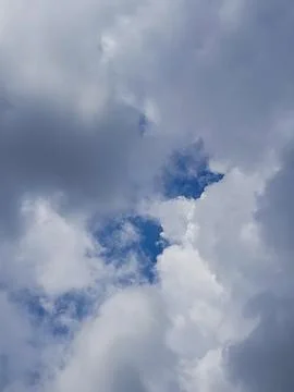 Dense clouds with a small opening revealing blue sky create a dramatic Stock Photos