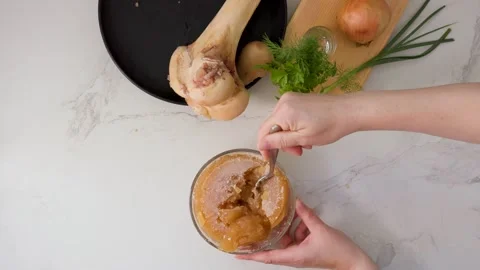 Dense, collagen-rich gelled bone broth texture tested with spoon in a premium Stock Footage 344032064