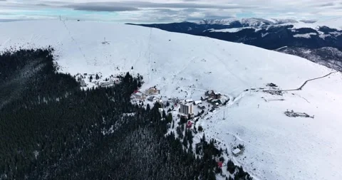 A dense evergreen spruce forest covers the white snow-capped hills Video stock 201491203