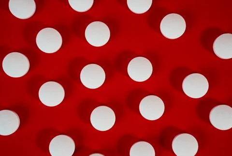 Dense field of white round tablets covering a red surface, minimal texture shot Stock Photos