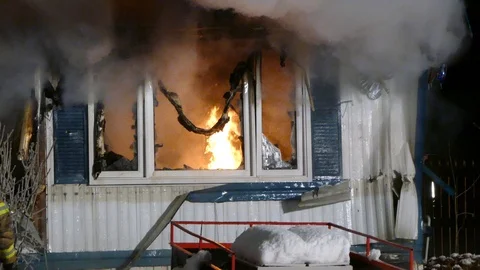 Dense flame burning inside trailer home in winter with broken windows Video stock 99009586