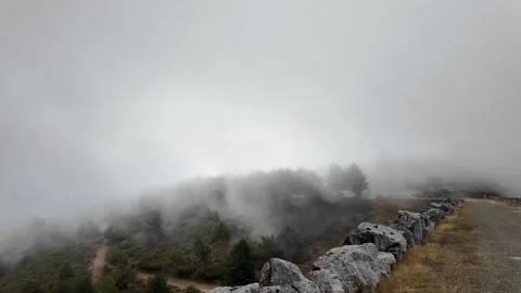 Dense fog moving over a mountain road and a stone wall during a misty weather Stock-Footage 345097634