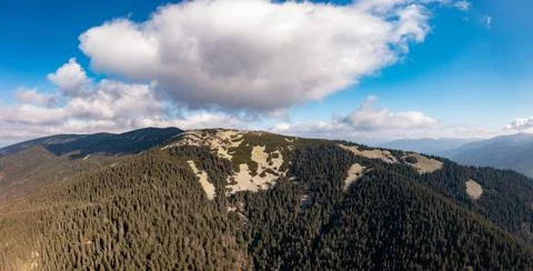 Dense forests on mountain peak under blue sky with clouds Stock Photos