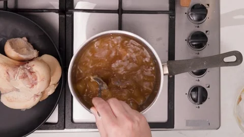 Dense, Gelatinous Bone Broth Cooling in a Stainless Pan, Spoon Testing Thickness Stock Footage 344031660