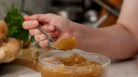 Dense gelatinous bone broth jelly in a glass cup with spoon, highlighting Stock Footage 344031599