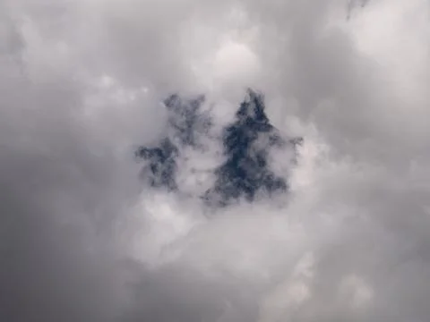 Dense gray clouds surrounding small opening of blue sky, creating moody Stock Photos