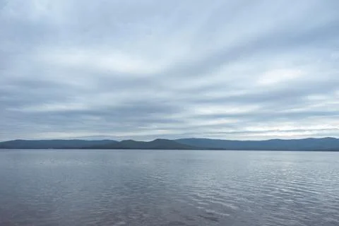 Dense gray thunderstorm cumulus clouds and a lake, water with waves. A gloomy Stock Photos