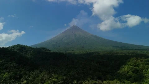 Dense green forest wraps around the volcanic base Vídeos de archivo 333330513